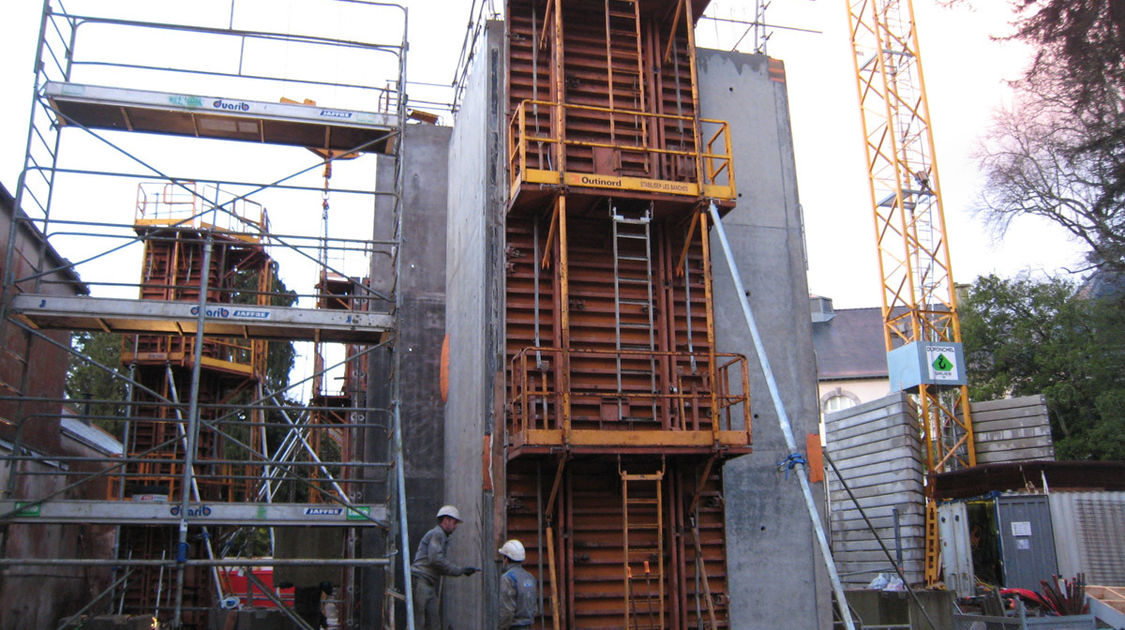 Chantier du pôle Max Jacob : sans à-coups et presque en silence, le grutier libère la paroi fraichement coulée de sa peau métallique. Le 19 décembre 2013